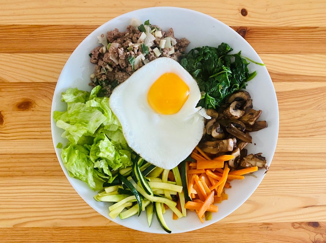 Bibimbap casero con huevo frito, carne, espinaca, zanahoria, zapallo y hongos